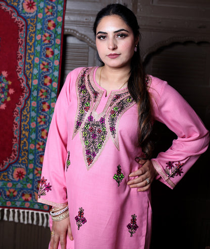 Woman wearing a pink embroidered traditional outfit with a colorful background